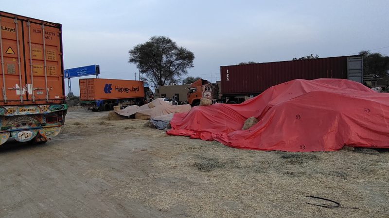 “Wheat straw bales ready for export – container trucks at Babar Aziz Balers (Pakistan)”.